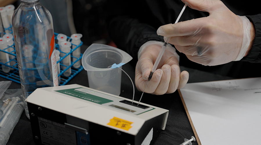 Un chercheur de l’Institut des sciences du sport Gatorade observe un échantillon de sueur à l’aide d’outils d’analyse de laboratoire pour mesurer la concentration d’électrolytes et les niveaux de sodium chez une joueuse de hockey.